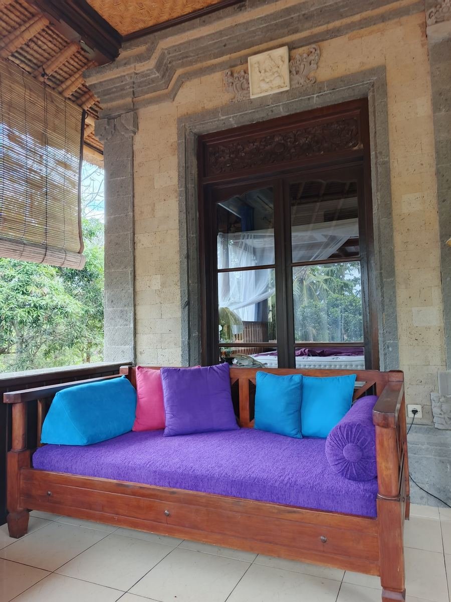 Teak daybed with blue and purple cushions on a Balinese terrace