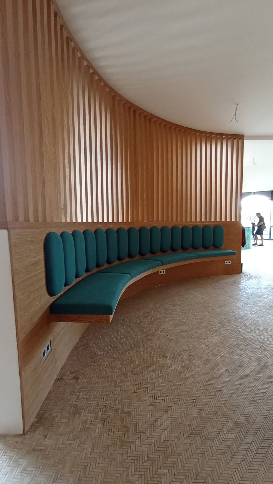Curved teal banquette set into a timber-slatted wall
