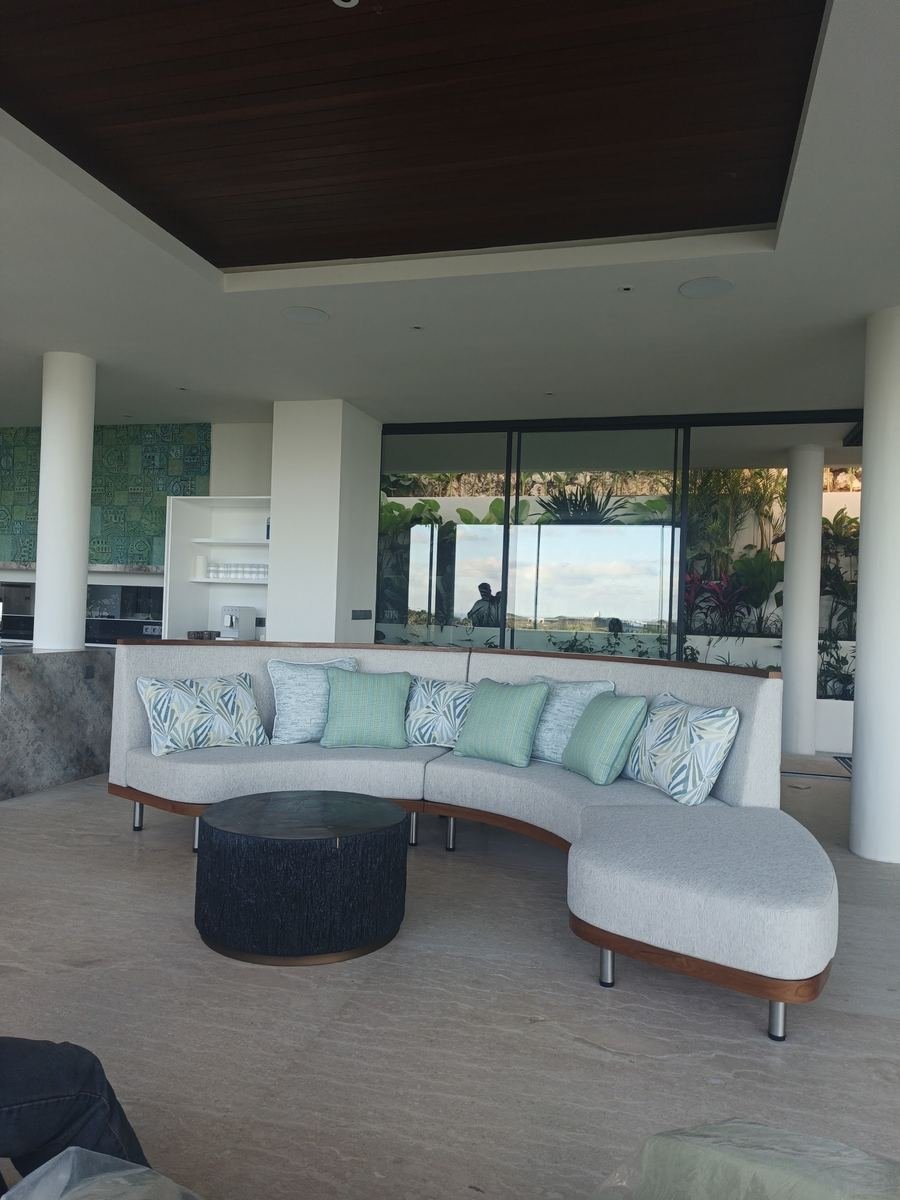 Curved white sofa with patterned cushions facing a glass wall