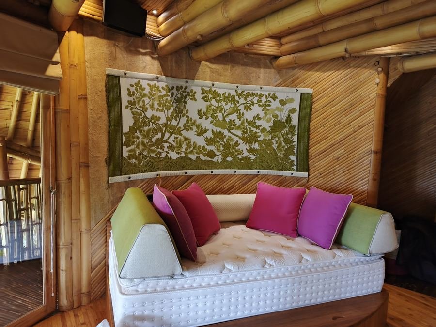 Daybed with pink, green and white cushions under a bamboo ceiling