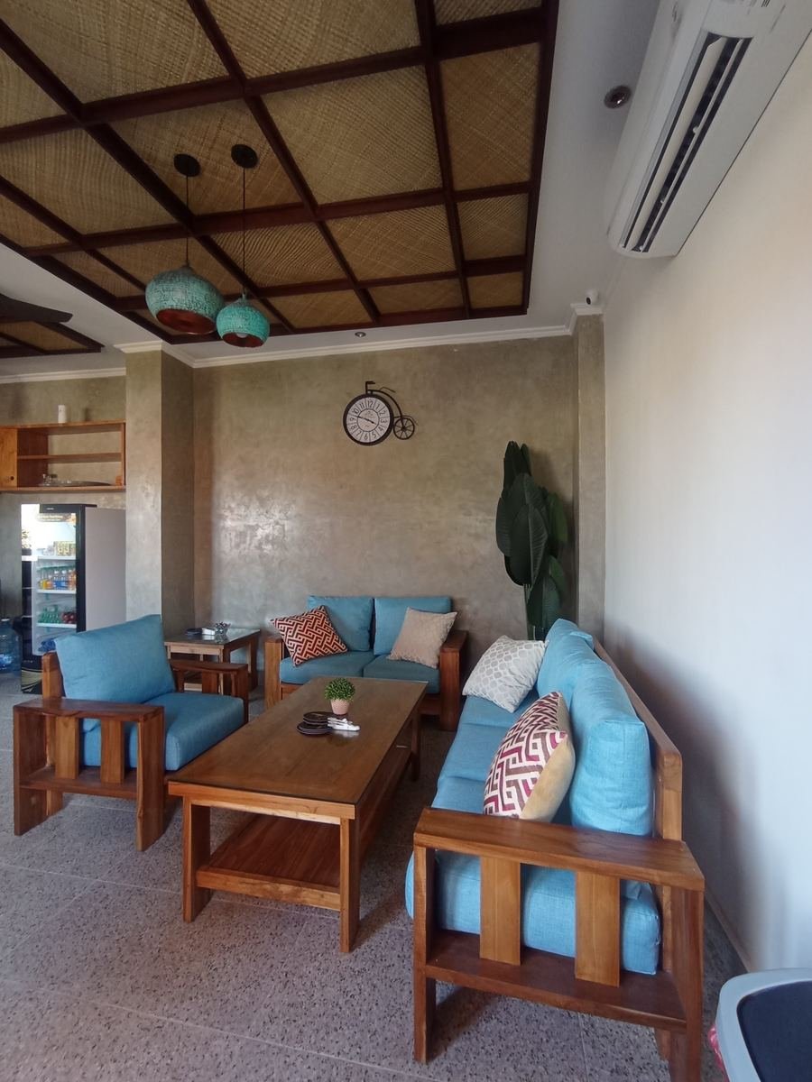 Teak sofas with teal cushions in a living room with a timber ceiling